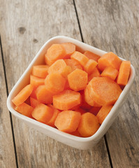 Carrots cut in bowl close up on wooden background