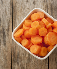 carrots cut in bowl close up on wooden background