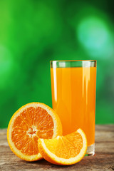 Glass of fresh orange juice on grey wooden background