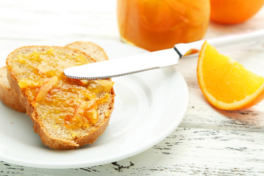 Bread with orange jam on white wooden background