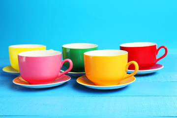 Colorful cups on blue wooden background