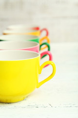 Colorful cups on white wooden background