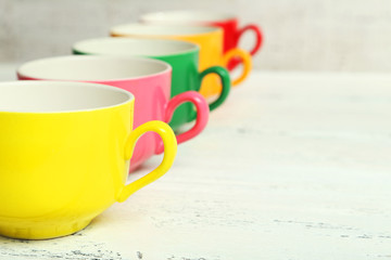 Colorful cups on white wooden background