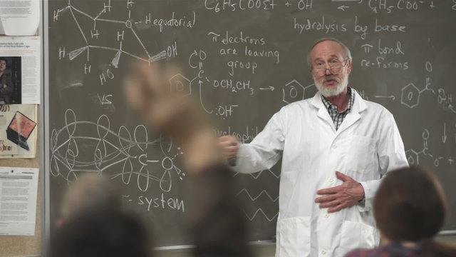 A college professor calls on a student raising their hand in class