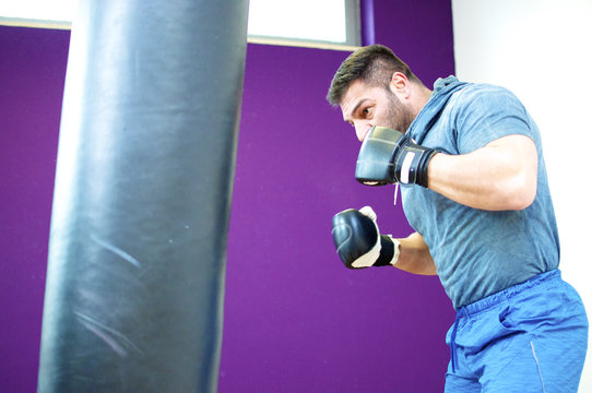 Beim Boxtraining - Mann mit Muskeln trainiert am Sandsack