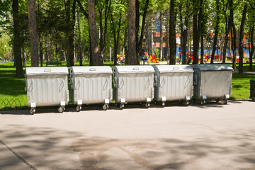 Several containers of trash on an asphalt site