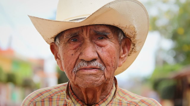 A old Mexican cowboy poses for the camera in a small town in Mexico