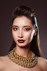 Studio beauty portrait of woman with gold necklace and make-up