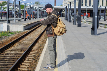 Obraz na płótnie Canvas Young man waits train on railway station
