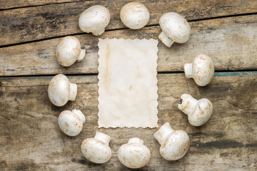 Mushrooms with blank paper sheet on wood background