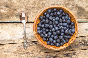 Clay bowl with fresh wild berries on wooden background