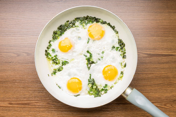 Fried eggs in frying pan on wood background