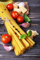 Raw pasta with cheese and vegetables on wooden background