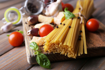 Raw pasta with cheese and vegetables on wooden background