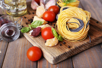 Raw pasta with cheese and vegetables on wooden background