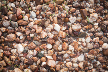 Small rocks cover a floor with some dirt and grass, Background a