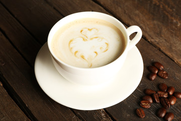 Cup of coffee latte art with grains on wooden background