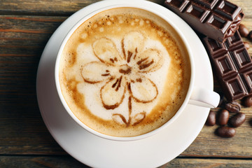 Cup of coffee latte art with grains and chocolate on wooden table, top view