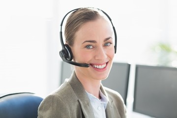 Smiling businesswoman with headset using computers