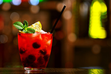 Glass of cocktail in bar on bright blurred background