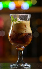 Glass of cocktail in bar on bright blurred background