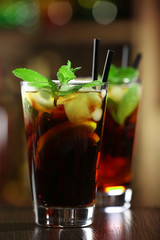 Glass of cocktail in bar on bright blurred background