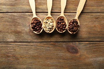 Coffee beans in spoons on wooden background