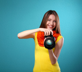 Obraz premium Young female photographer taking photos on blue background