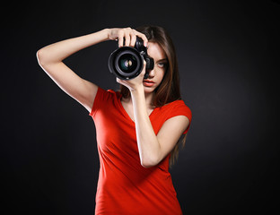 Young female photographer taking photos on black background