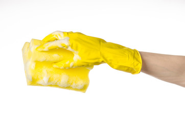 Hand holding a yellow sponge wet with foam  in studio gloves