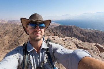 Cowboy backpacker selfie on mountain above Red sea Eilat city.