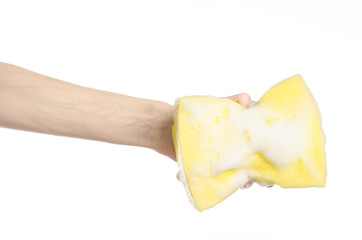 Hand holding a yellow sponge wet with foam isolated studio
