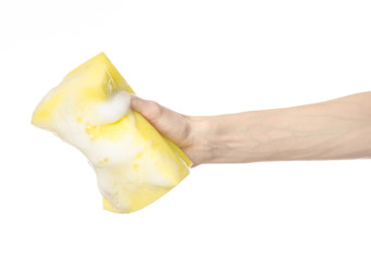 Hand holding a yellow sponge wet with foam isolated studio