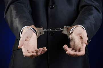 businessman in a black suit with handcuffs on his hands studio