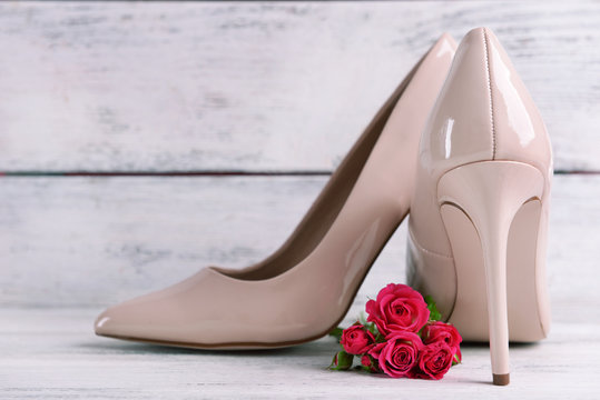 Female shoes with flowers on wooden background