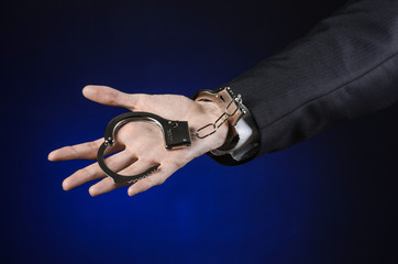 Fototapeta premium businessman in a black suit with handcuffs on his hands studio