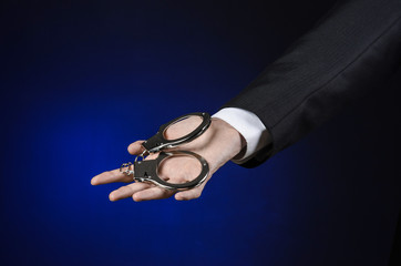 businessman in a black suit with handcuffs on his hands studio