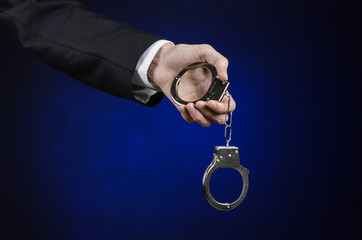 businessman in a black suit with handcuffs on his hands studio