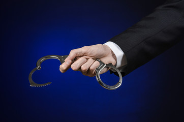 businessman in a black suit with handcuffs on his hands studio