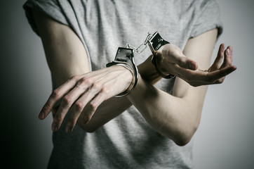 man with handcuffs on his hands in a gray T-shirt  in the studio