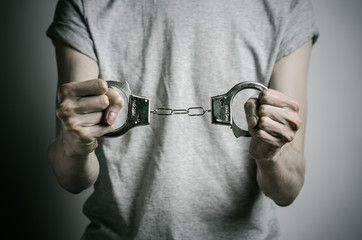 Fototapeta premium man with handcuffs on his hands in a gray T-shirt in the studio