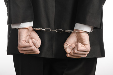 businessman in a black suit with handcuffs on his hands studio