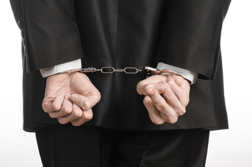 businessman in a black suit with handcuffs on his hands studio