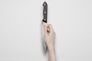 A man's hand reaching for a knife isolated on a gray background