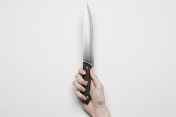 A man's hand reaching for a knife isolated on a gray background