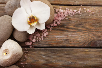 Spa stones and orchid flower on wooden background