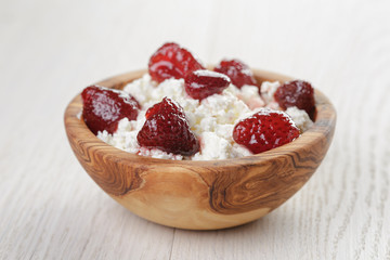 cottage cheese with preserved strawberry in wood bowl on oak
