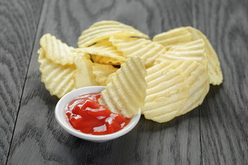 rippled organic chips wit tomato sauce on wooden table