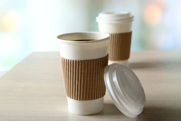 Paper cups of coffee on table on bright background