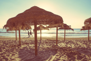 Wooden umbrellas in a beach at sunset
